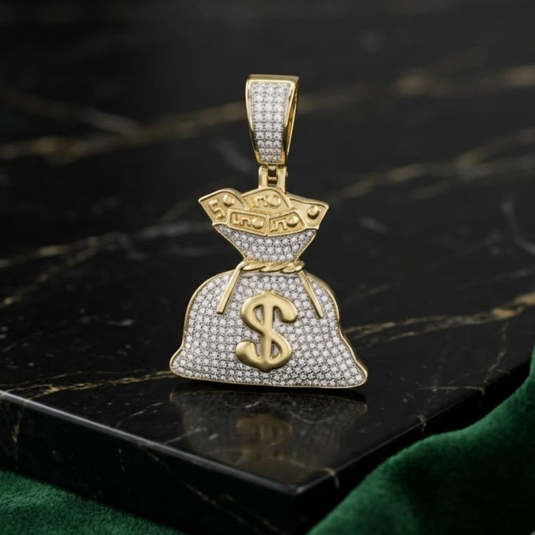 The 10K Gold Diamond Money Bag Pendant 1/2 CTTW, featuring sparkling stones in 10K yellow gold, sits on a dark marble surface with green velvet fabric nearby.