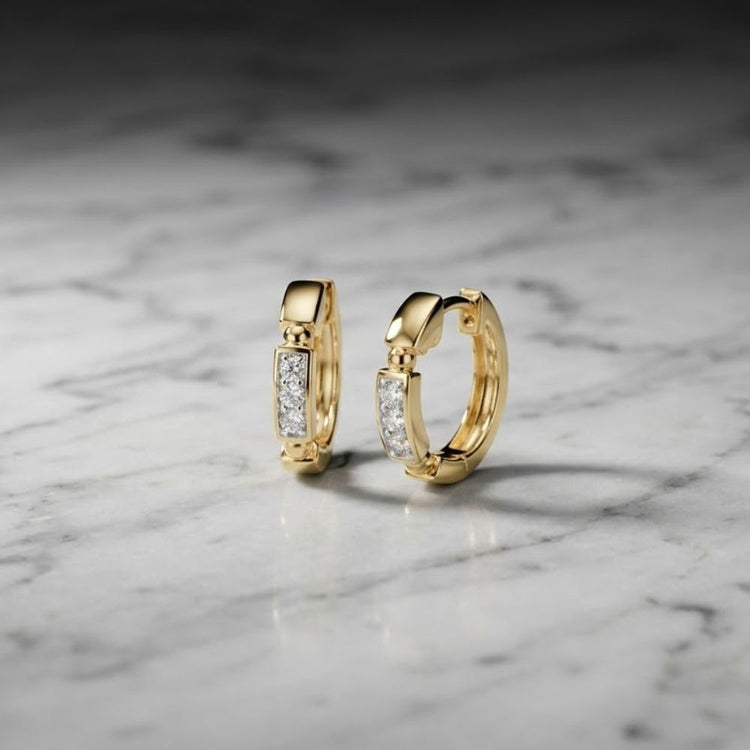 The 10k Gold Diamond Fashion Hoop Earrings 1/10CTW are displayed standing upright on a white marble surface with gray veining, illuminated by soft, natural light.