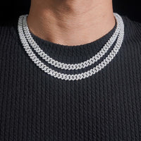 A person wearing a ribbed black shirt and two layered necklaces—an 8mm Moissanite Cuban Links Chain in 925 Sterling Silver and another bold Cuban link.
