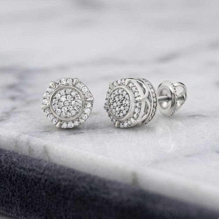 A pair of 1/4CTW Natural Diamond Gift Earrings in sterling silver rests on a white marble surface.