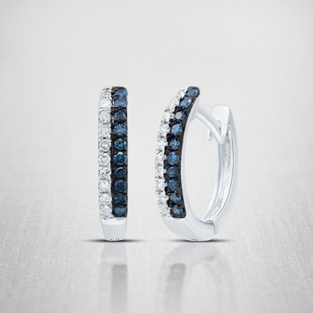 A pair of 10K Blue Diamond Huggie Earrings (1/5 CTTW Gold) featuring two rows—one of dark blue diamonds and one of clear stones—set on a light, textured background.
