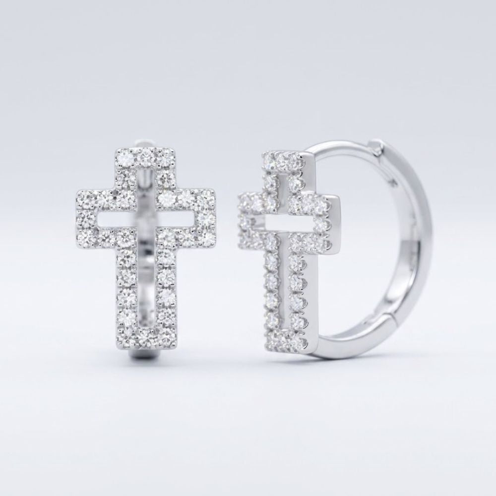 The 10k Gold Diamond Cross Huggie Hoop Earrings 1/3CTW showcase cross-shaped pendants encrusted with sparkling diamonds, elegantly displayed against a plain light gray background.