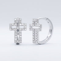 The 10k Gold Diamond Cross Huggie Hoop Earrings 1/3CTW showcase cross-shaped pendants encrusted with sparkling diamonds, elegantly displayed against a plain light gray background.