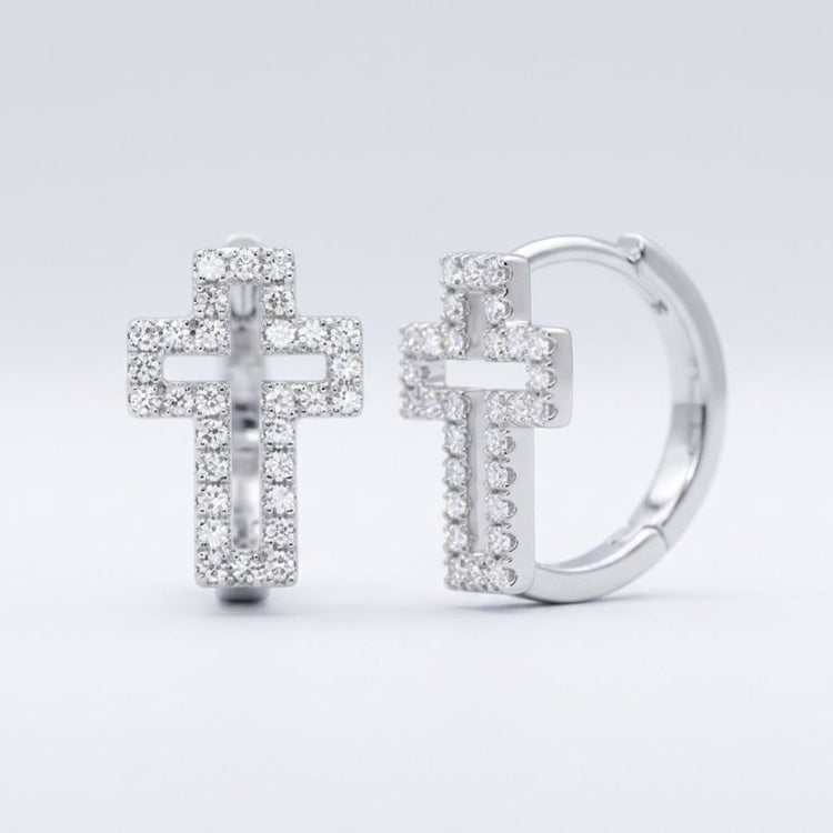 The 10k Gold Diamond Cross Huggie Hoop Earrings 1/3CTW showcase cross-shaped pendants encrusted with sparkling diamonds, elegantly displayed against a plain light gray background.