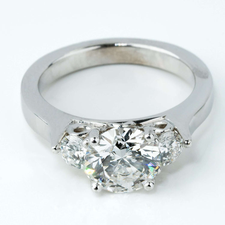 The 3.08CTW Round Trilogy Lab Diamond Engagement Ring features a large center lab diamond flanked by two smaller rounds, elegantly set in 14k white gold and displayed on a plain white background.