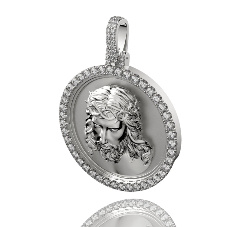 The 14K Gold Diamond Jesus Face Round Pendant, showcasing a bearded face with a crown of thorns and encircled by shimmering diamonds, is displayed on a reflective surface.