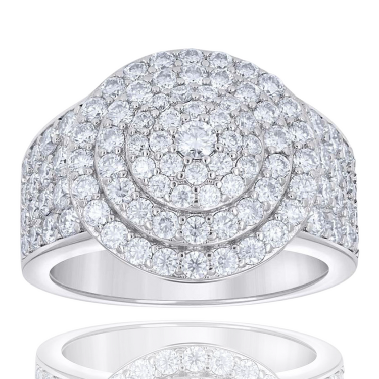 The Mens Moissanite Round Head Cluster Fashion Ring features three concentric circles of sparkling moissanite stones and additional stones on its wide, highly polished sterling silver band, beautifully reflected on a white surface.