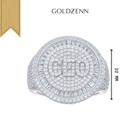 The Baguette Moissanite CEO Round Head Fashion Ring features “CEO” in the center, surrounded by rows of moissanites and baguette-cut stones, measures 22mm high, with "GOLDZENN" above and a gold ribbon in the top left corner.