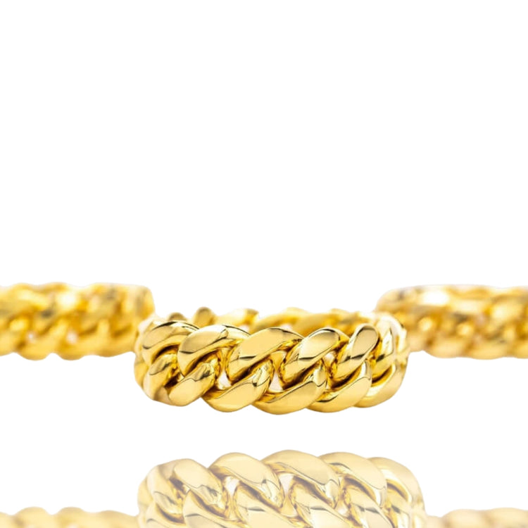 The 8mm Miami Cuban Link Ring in solid gold is displayed on a white background with its reflection below. Two similar gold chain pieces, echoing the ring's Cuban link design, are partially visible on either side.