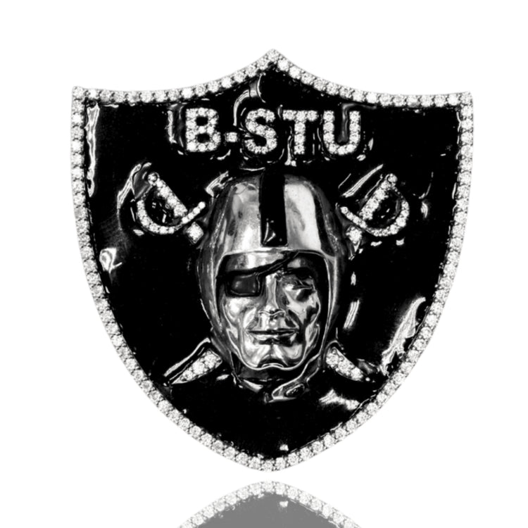The Raiders Custom Pendant Moissanite – 14K White Gold is a black shield-shaped pin featuring a silver helmeted face with eyepatch, crossed swords, and "B. STU" above, bordered with sparkling moissanite stones for a luxe finish.