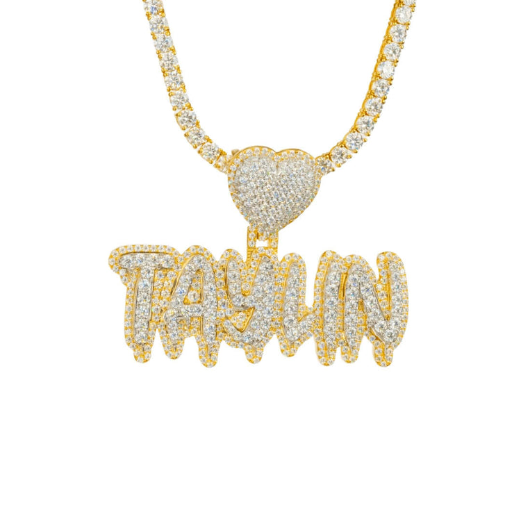 A bold Custom Diamond Name Pendant - Solid Yellow Gold, spelling TAYLIN in sparkling diamond-encrusted letters, paired with a 14K gold necklace and a heart-shaped diamond pendant.
