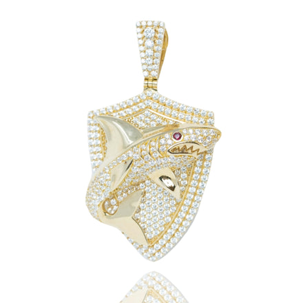 Men’s Shark Pendant in 10k Gold with CZ features a shield design and a 3D shark with a red gemstone eye, set against a sparkling CZ background.