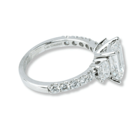 The 3.8 CTW 14k White Gold Three Stone Emerald Engagement Ring features a large emerald-cut diamond with two smaller lab-grown diamonds, round accents, and "Lab Created" engraved inside the band.