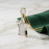 The 14K Gold Diamond Star Charm Pendant 3/4 CTTW, crafted in yellow gold and adorned with sparkling diamonds, is displayed on a gold chain resting atop marble beside a folded green cloth.