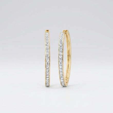 The 14k Yellow Gold Diamond Fashion Hoop Earrings 7/8CTW are shown upright on a plain white background, featuring hoops encrusted with small natural diamonds along the front outer edge.
