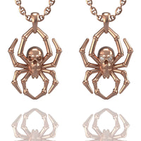 Displayed side by side on a white background are two rose gold 14k Gold Spider Skull Pendants, each featuring a skull at the center of a spider design and hanging from matching chains.