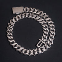 The Moissanite Cuban Links Chain 18mm in 925 Sterling Silver, featuring a box clasp, is displayed on a dark surface in a loose circular shape.