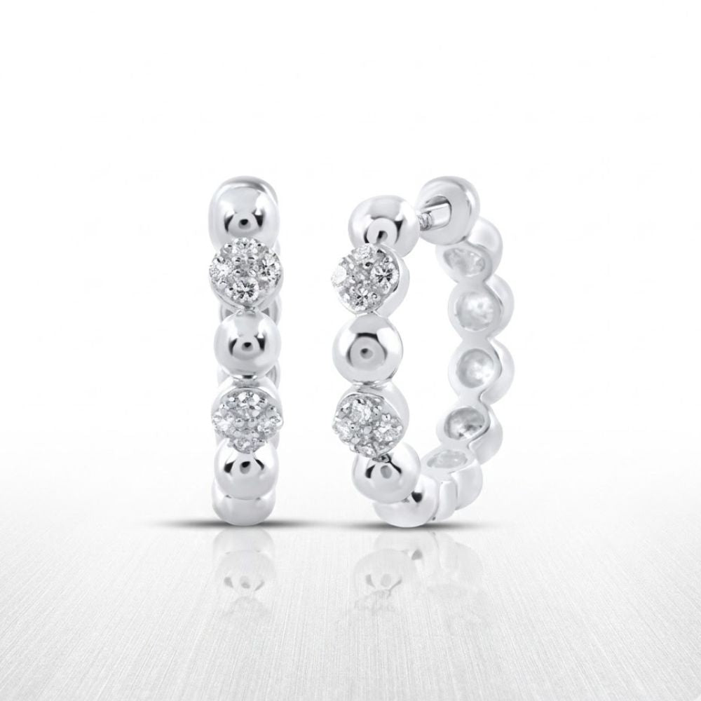 The 10K Diamond Hoop Earrings 1/10 CTTW Gold Hoops feature alternating silver beads and sparkling clear gemstones, beautifully displayed on a reflective white surface.