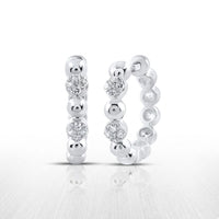 The 10K Diamond Hoop Earrings 1/10 CTTW Gold Hoops feature alternating silver beads and sparkling clear gemstones, beautifully displayed on a reflective white surface.