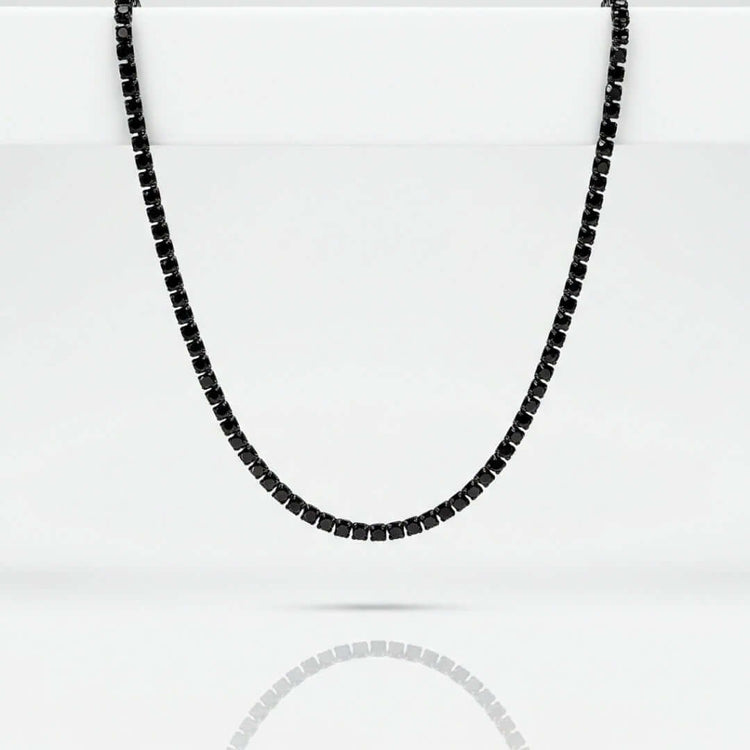 The Black Moissanite Tennis Chain - 3mm is shown on a plain white background, its minimalist black stones and necklace reflected below.