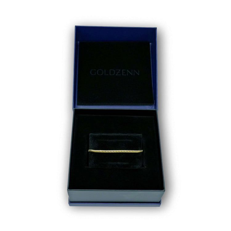 A Cuban Link Bracelet - 3mm, made of solid gold, is displayed in a black velvet-lined box with GOLDZENN printed inside the lid. The open box is positioned against a clean white background.