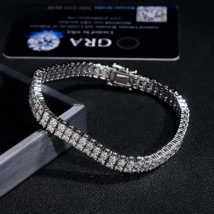 A close-up of the Double Row Moissanite Silver Bracelet - 3mm, crafted from 925 sterling silver with square-cut stones, displayed on a dark surface beside a black certification card.