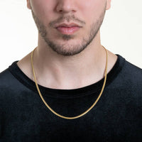 A close-up of a man wearing a black shirt and the Cuban Link Chain Solid Gold - 3mm, with only the lower half of his face and neck shown against a plain background.