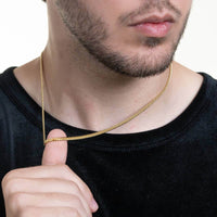 A man in a black shirt showcases the Cuban Link Chain Solid Gold - 3mm necklace around his neck, his face partially visible with a neatly trimmed beard.
