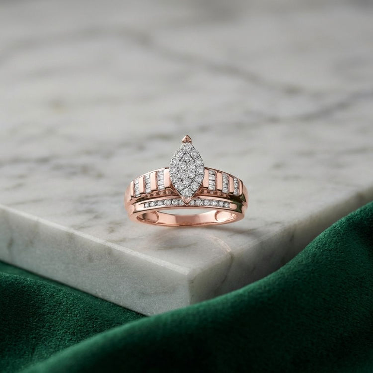 A 10k Gold Oval Diamond Cluster Bridal Ring (1/2 Cttw) rests on a white marble surface, with a green velvet cloth in the foreground.