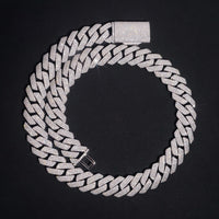 The Moissanite Cuban Links Chain 20mm - 925 Sterling Silver is displayed in a circle on a black background, highlighting its sparkling interlocking links and bold rectangular clasp.