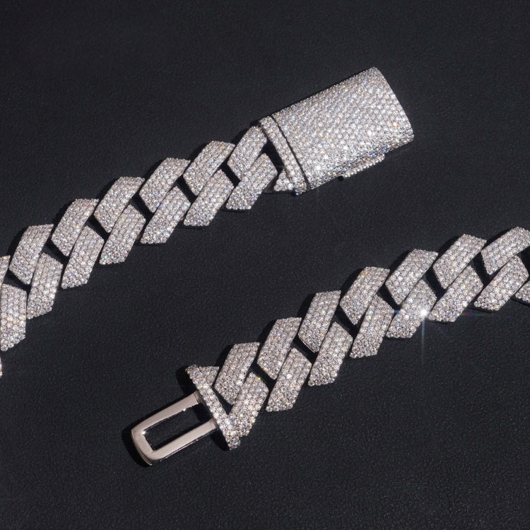 A close-up of the Moissanite Cuban Links Chain 18mm - 925 Sterling Silver, featuring a box clasp, is displayed on a black surface. Its metal links are encrusted with sparkling moissanite stones.