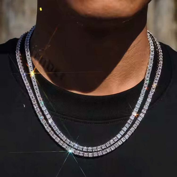 A person in a black shirt wears two layered Asscher Cut Moissanite Tennis Chains - 4mm, crafted from hypoallergenic 925 sterling silver that catches the light with star-like reflections.