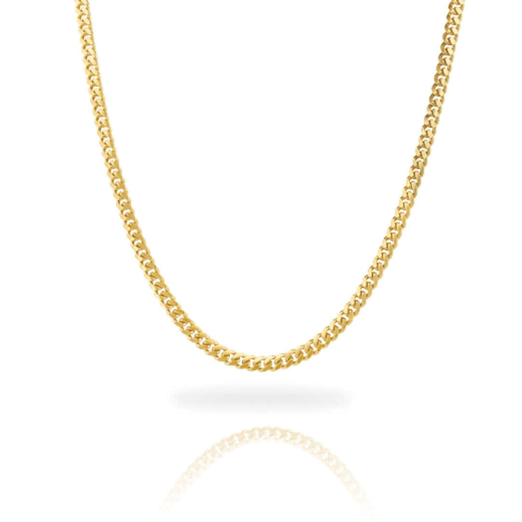 The Cuban Link Chain Solid Gold 4mm - Box Lock is featured against a white background. Its classic curb link design forms a smooth curve, with the gold chain and its reflection visible below.