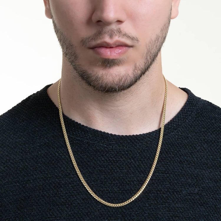 A close-up shot of a man wearing a textured black shirt and the Cuban Link Chain Solid Gold 4mm - Box Lock, shown from the shoulders up with only the lower half of his face visible.
