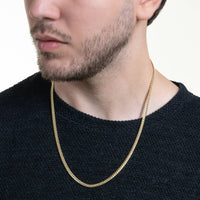 A man in a textured black sweater wears the Cuban Link Chain Solid Gold 4mm - Box Lock necklace, shown from the shoulders up with his face partially out of frame.