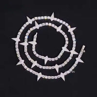 The Thorny Moissanite Tennis Chain - 4mm is displayed in a spiral on a black background, showcasing alternating square and star-shaped segments for a striking effect.