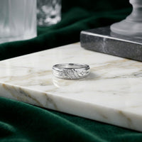 A 10k gold diamond matching wedding ring set rests on a white marble surface, surrounded by green velvet fabric and glass decor in the background, creating an elegant scene reminiscent of exquisite diamond wedding bands.