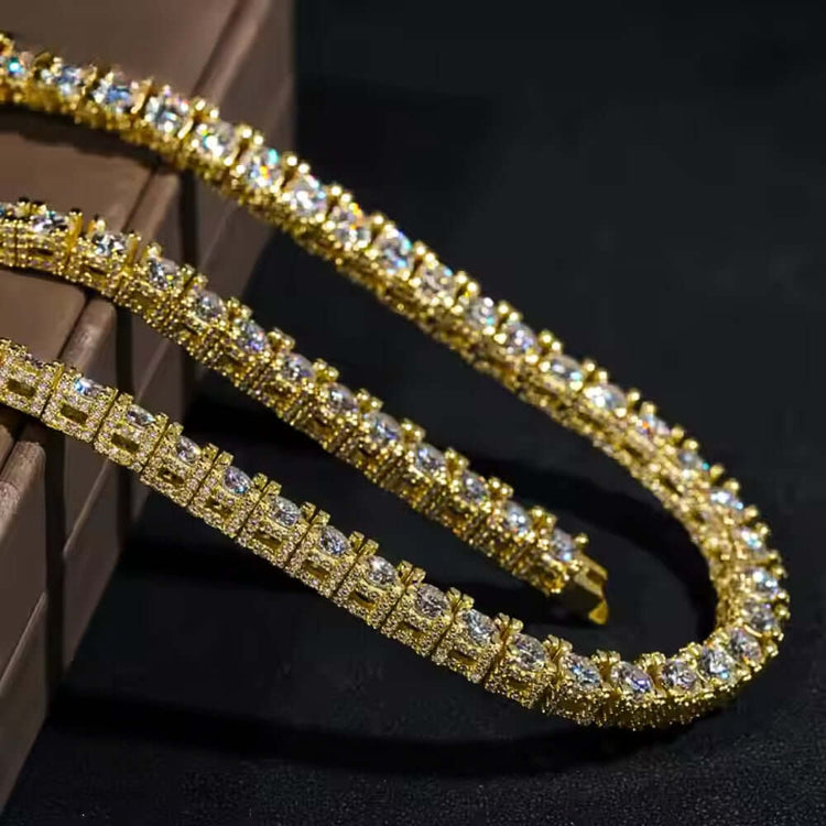 A close-up of the Fully Ice Moissanite Tennis Chain - 5mm, encrusted with sparkling gemstones, displayed on a dark surface beside a brown box.