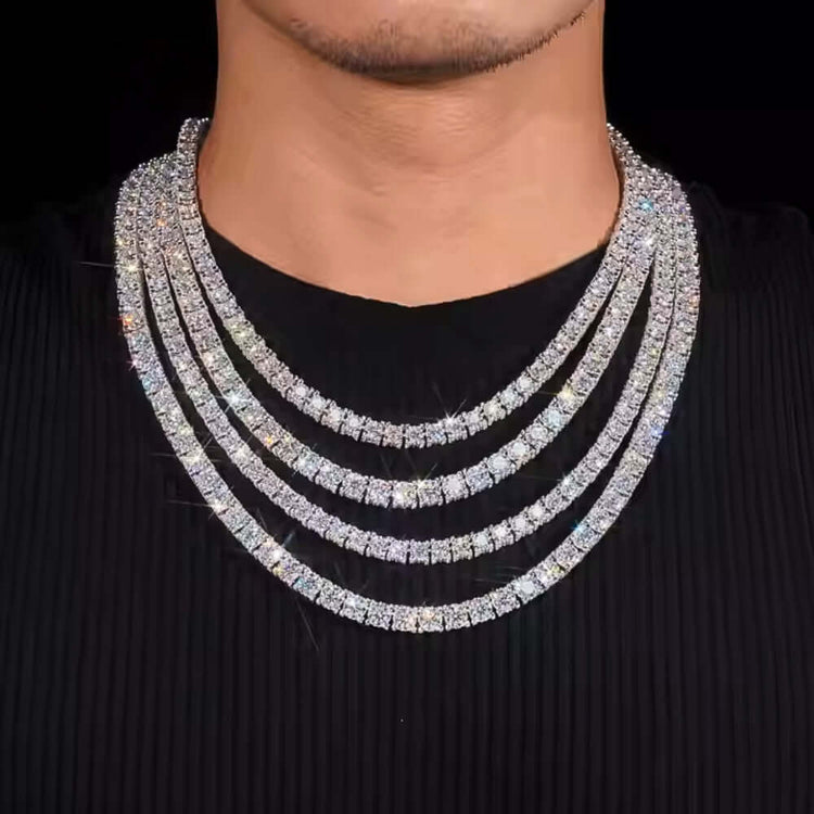 A person wearing a black shirt showcases four layered Iced Out Moissanite Tennis Chains (5mm), their sparkling silver shine standing out against a black background.