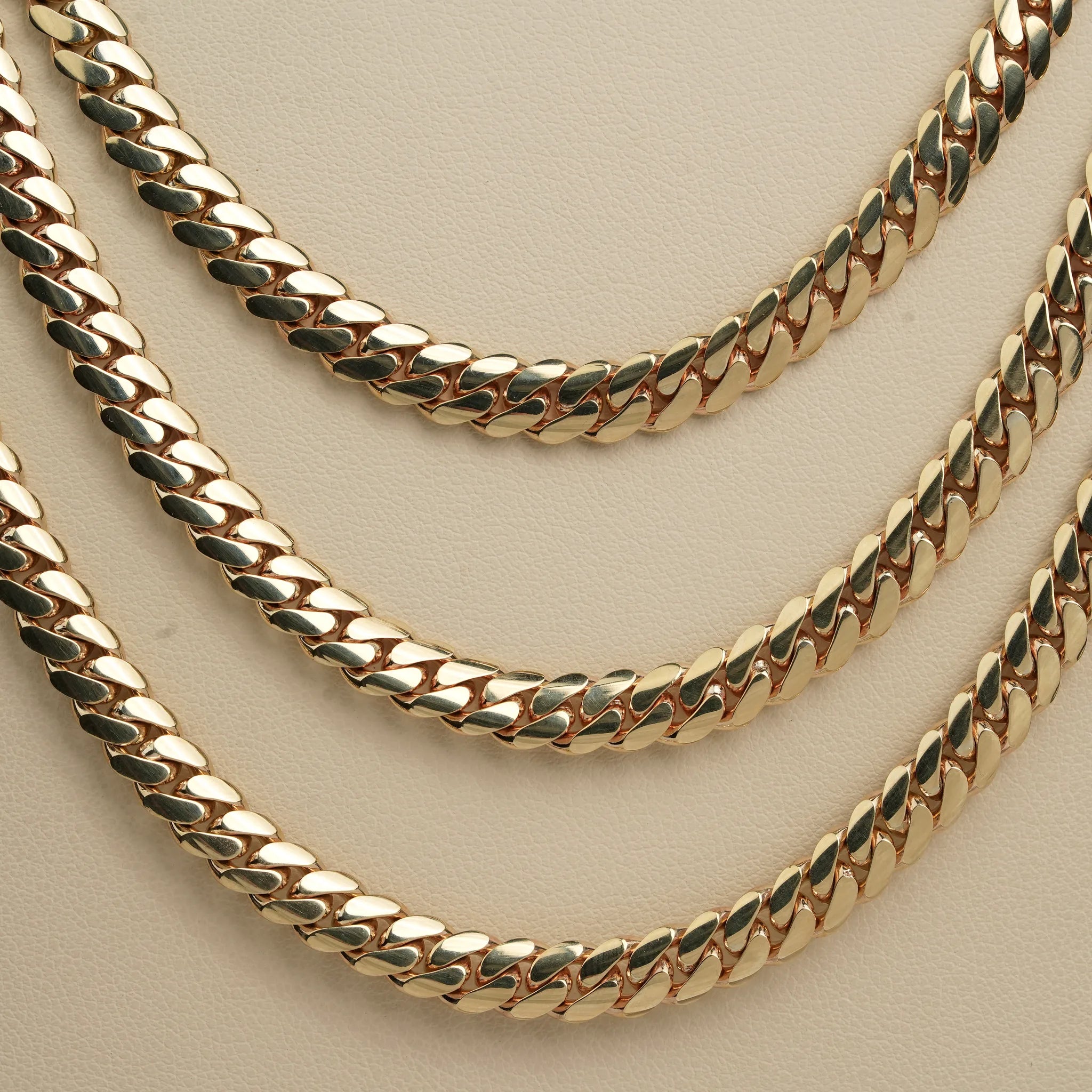 The 6mm Handmade Miami Cuban Link Chain in 10K/14K solid gold is displayed on a beige surface, highlighting its polished links and elegant craftsmanship—a ready-to-ship classic of Miami jewelry.