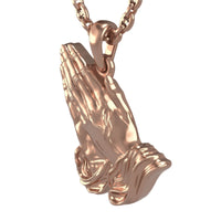 The 14k Gold Praying Hands Pendant features two hands pressed together in prayer, crafted in rose gold and hanging gracefully from a matching chain.