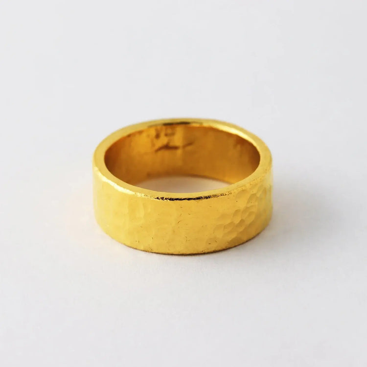 The 8mm, 24k Hammered Flat Band features a wide, textured surface and comfort-fit design, shown on a plain white background.