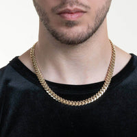 A man with light facial hair wears the Cuban Link Chain Solid Gold - 9mm and a black shirt, shown from neck to upper chest against a plain background.