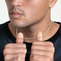 A man in a black shirt stretches a Beads Chains necklace made of 10K gold beads with both hands near his neck, highlighting its elegant design and texture.