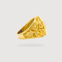 The Blue Stone Signet Ring in Solid Gold features a thick band with intricate, raised floral and leaf patterns, displayed against a plain light gray background.
