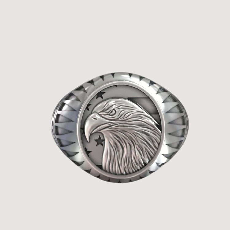The Bold Eagle Liberty Statue Ring features a silver band with an engraved eagle head in profile, accented by stars and a decorative border—perfect for those who love the striking style of a gold eagle ring.