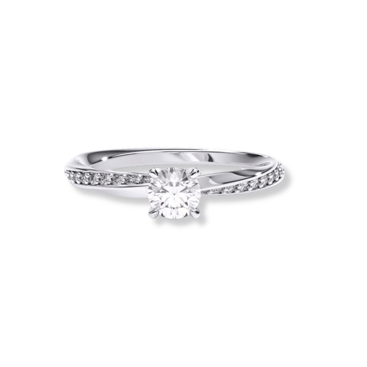 The Brilliance Eternity Lab Grown Diamond Engagement Ring is a silver women’s ring with a round center diamond and small diamonds set along one side of the twisted band, displayed on a white background.