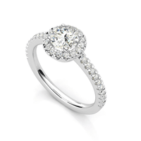 The Brilliance Halo Diamond Ring features a radiant round center diamond, a halo of smaller diamonds, and a pavé band, shown on a white background.