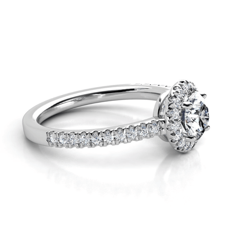 The Brilliance Halo Diamond Ring showcases a radiant round center diamond encircled by a shimmering halo, with pavé-set diamonds adorning its elegant white gold band.