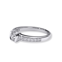 The Classic Channel-Set Lab Diamond Engagement Ring features a round solitaire lab diamond in a white gold prong setting, with smaller diamonds channel-set along the upper band—a timeless choice for women's engagement rings.